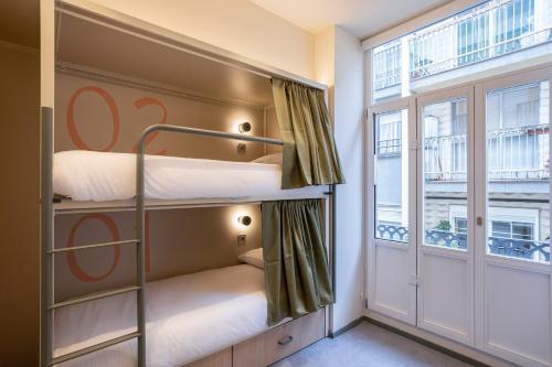 Una habitación con literas con dos literas y una ventana. en Camila Hostel Valencia, en Valencia