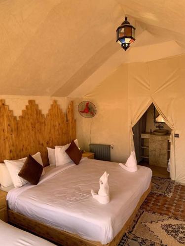 two white birds sitting on a bed in a tent at Desert cmp luxury in Merzouga