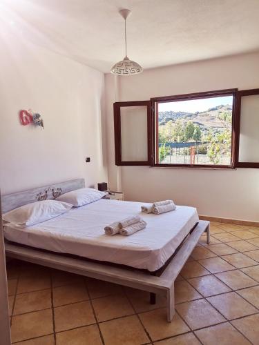 a bedroom with a large bed with a window at Villa Su Navru in Irgoli