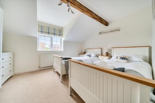 a white bedroom with two beds and a window at Avocet Cottage in Brancaster