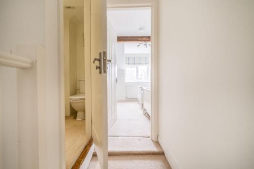 a corridor of a bathroom with a toilet and a door at Avocet Cottage in Brancaster