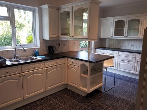 Una cocina con gabinetes blancos y una encimera negra. en Hendon Home, en Hendon