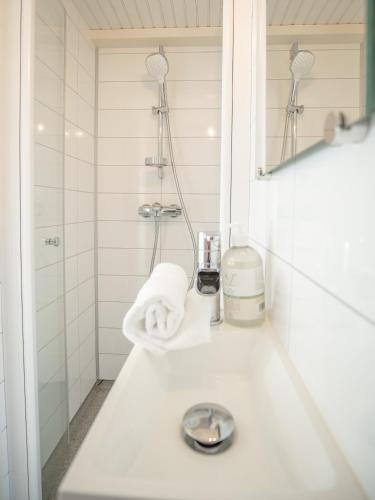 a white bathroom with a sink and a shower at Olenilsøya Mini Villa in Reine