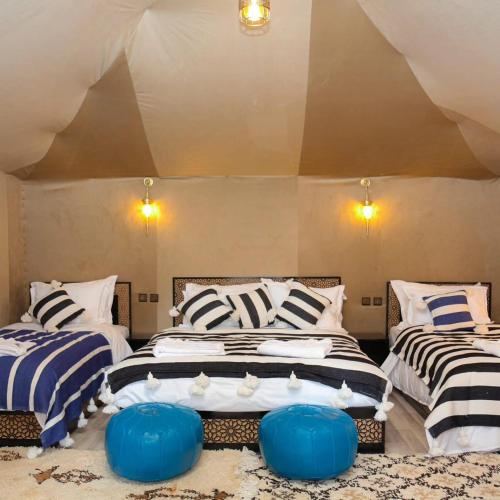 two beds in a room with blue and white stripes at Dream Luxury Majestic Camp in Merzouga