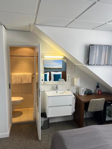a bathroom with a sink and a desk in a room at Hotel De Koningshof in Noordwijk aan Zee