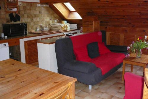 a living room with a red couch in a kitchen at Le Mas du Plan in Le Bourg-dʼOisans