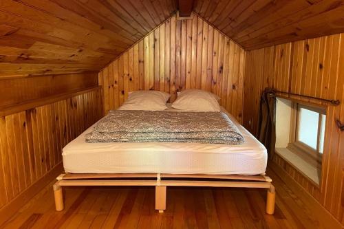 a bed in a wooden cabin with a window at Le Mas du Plan in Le Bourg-dʼOisans