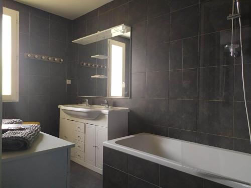a bathroom with a tub and a sink and a mirror at Le cheiron in Coursegoules