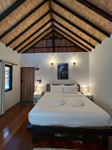 a bedroom with a large white bed with wooden ceilings at Coco Valley Koh Tao in Ko Tao