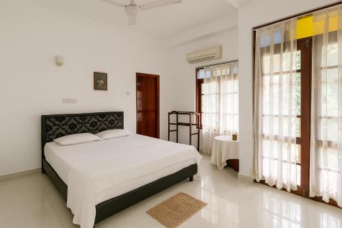 Un dormitorio blanco con una cama grande y ventanas en Mirissa Eye Beach Hotel and Restaurant, en Mirissa