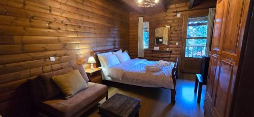 a bedroom with a bed and a couch in a log cabin at Panorama Elati in Elati Trikalon