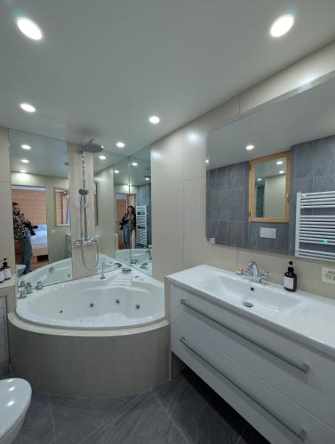 Un baño con dos lavabos, una bañera y un inodoro. en Appt de charme dans chalet - cosy & nature, en Villars-sur-Ollon