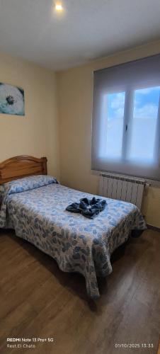 a bedroom with a bed and a large window at Hostal Hotel EL Chato in El Barraco