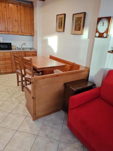 a kitchen with a wooden table and a red couch at La Baita del Sagittario in Prato Nevoso