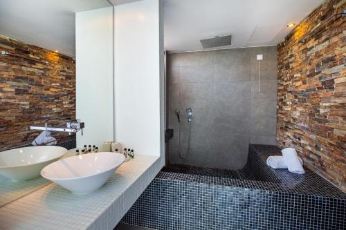 Un baño con bañera, lavabo y ducha. en Kamari Beach Hotel, en Potos