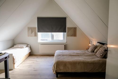 - une chambre mansardée avec 2 lits et une fenêtre dans l'établissement Holiday home with sauna on Panjevaart - VP100, à Hoeven