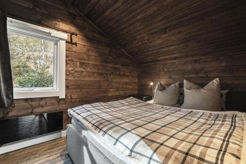 Schlafzimmer mit Holzwänden und einem Bett mit Fenster in der Unterkunft Unique 'Stabbur' in Hemsedal, view to skislopes in Kyrkjebøen