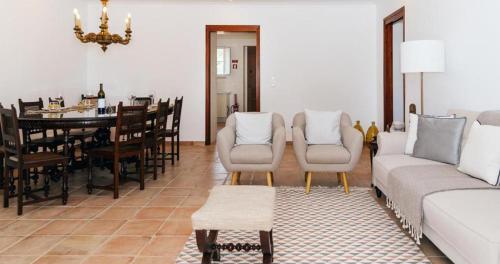een woonkamer met een bank en een eetkamer bij Ria Endless South - Barroca Village - Sítio da Fortaleza in Tavira