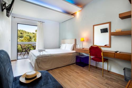 Un dormitorio con una cama y un escritorio con espejo. en Kamari Beach Hotel, en Potos