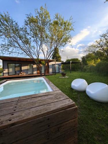 a backyard with a swimming pool and two white chairs at La Recompensa Tiny in Colonia Nuevo Paysandú