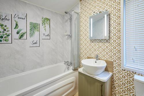 Un baño con lavabo y bañera y un lavabo. en Lucky Lodge with Hot Tub, en York