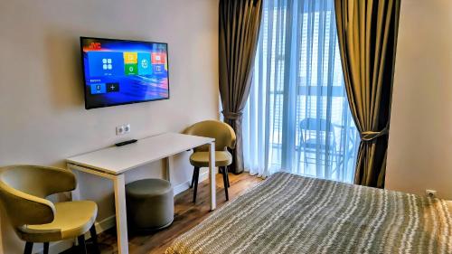 a hotel room with a desk and a tv on the wall at Billionare by Alliance Palace in Batumi