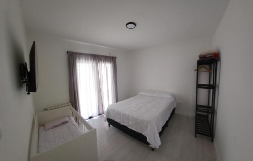 een witte slaapkamer met een bed en een raam bij El Rincón de Gemma in Salta