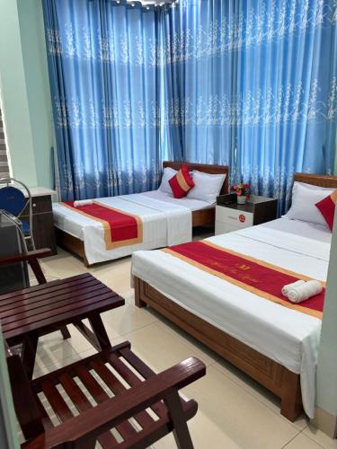 クアンガイにあるMINH THU MOTELの青いカーテンが備わる客室のベッド2台