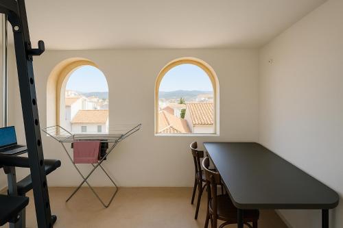 a room with two windows and a table and chairs at Comfortable house in Oliena