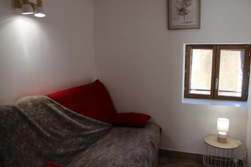 a bedroom with a red couch and a window at L'ecureuil de luceram in Lucéram