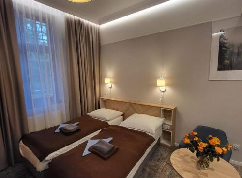 a hotel room with two beds and a table at Sanatorium Gryf in Połczyn-Zdrój