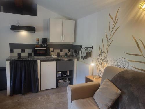 a living room with a couch and a kitchen at L'ombre du vent in Contes
