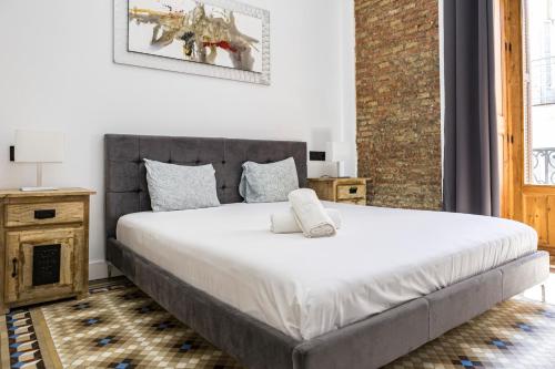 a bedroom with a large bed with white sheets at NOMADIA en Plaza de la Constitucion 1 in Málaga