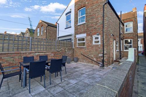 a patio with a table and chairs and a brick building at Home Away I 3BR Comfort Suite I Private Courtyard I Super Fast Wi-Fi I Free Parking in Bedford