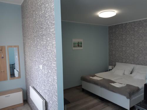 a bedroom with a bed and a brick wall at Margaréta Studió Apartman in Pusztavacs