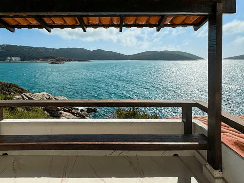 a bench sitting on a porch looking at the water at Pousada Vista Grega in Arraial do Cabo