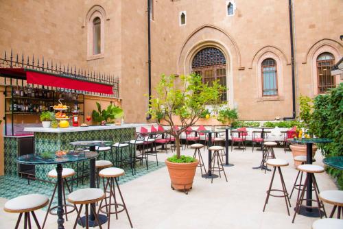 eine Terrasse mit Tischen und Hockern vor einem Gebäude in der Unterkunft Hotiday Roma Borghese in Rom