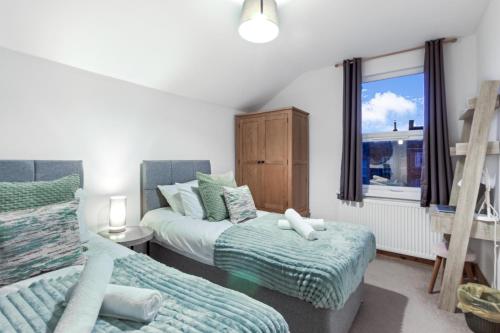 ベッドフォードにあるLuxeVille I Serene 3BR Apartment with Private Courtyard I LongTerm RatesI ParkingI WiFiのベッド2台と窓のある寝室