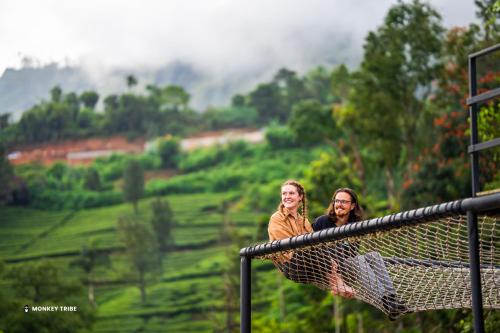 Dos personas sentadas en una hamaca con vistas a un valle en Monkey Tribe Munnar, en Munnar