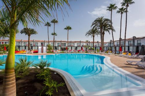 a pool at a resort with palm trees and chairs at Sholeo Lodges Maspalomas in Playa del Ingles