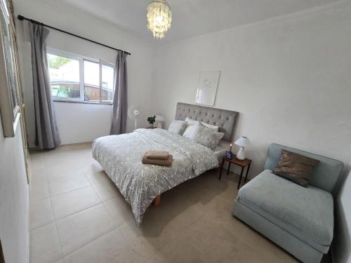 een slaapkamer met een bed, een bank en een stoel bij Dias de sol in Fuzeta