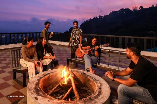 un grupo de personas sentadas alrededor de una hoguera en Monkey Tribe Munnar, en Munnar