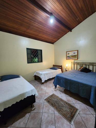 a bedroom with two beds and a wooden ceiling at Refúgio com Piscina, Churrasco e Lazer no Campo in Sumaré