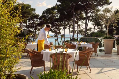 Un hombre de pie en una mesa en un restaurante. en Hotel Bellevue, en Mali Lošinj