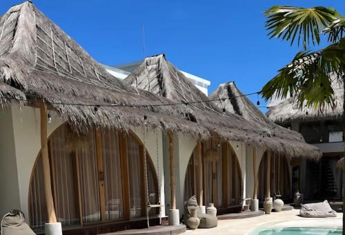 a building with a thatched roof next to a pool at Lahima Cabanas in Dickwella