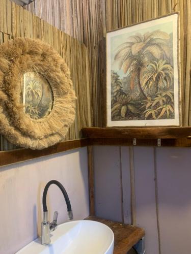 a bathroom with a sink and a picture of palm trees at Emelios Lodge Océan View in Port Mathurin
