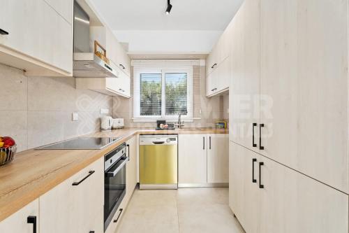 a white kitchen with white cabinets and a sink at Apartment Themis in Protaras
