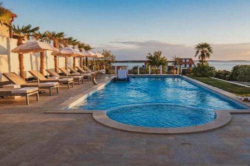 a large swimming pool with chairs and a view of the ocean at Family-friendly apartments with swimming pool Mandre, Pag - 24196 in Kolan