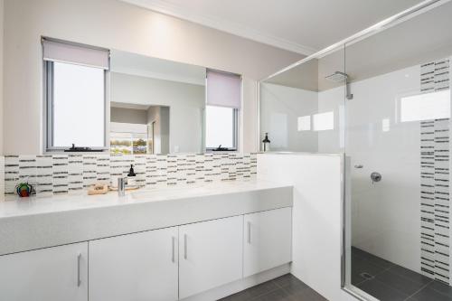 een witte badkamer met twee wastafels en een douche bij Two-Storey Lakeview Retreat at Dunsborough Lakes in Dunsborough