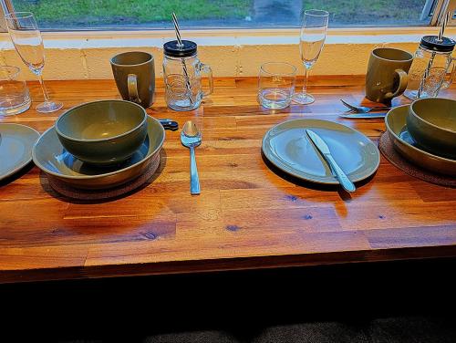 ein Holztisch mit Tellern, Löffeln und Gläsern in der Unterkunft Peaceful, Modern, LowToxic, Bfast included in Brisbane